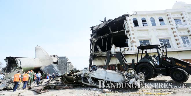 TINGGAL PUING: Personel TNI bersama Petugas PMI dan Basarnas menggunakan alat berat melakukan evakuasi pesawat Hercules C-130 yang jatuh di Jalan Jamin Ginting, Medan, Sumatera Utara.