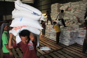 Petugas gudang Bulog sedang memindahkan beras dari gudang ke dalam truk untuk didistribusikan ke daerah dalam bentuk bantuan.
