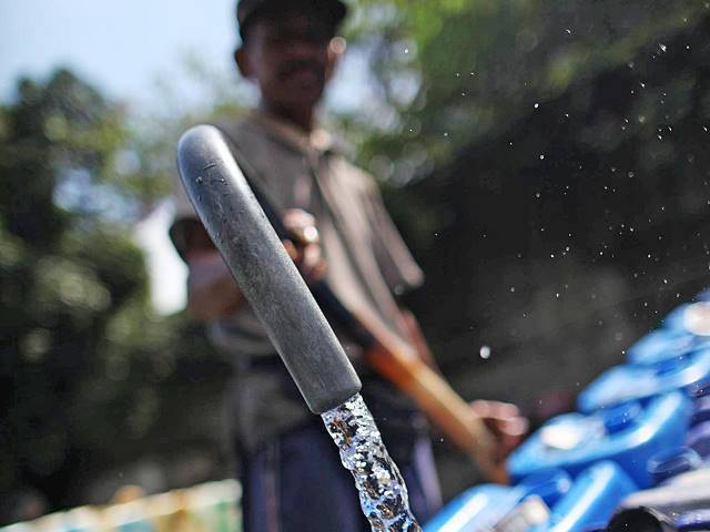 ILUSTRASI ISI AIR: Seorang petugas saat mengisi pasokan air bersih bagi warga.