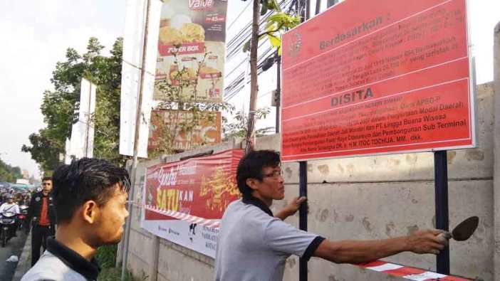 BERI TANDA: Petugas dari Kejaksaan Negeri (Kejari) Kota Bandung memasang plang pengumuman penyitaan tanah Cibeureum karena masih bermasalah dengan hukum.