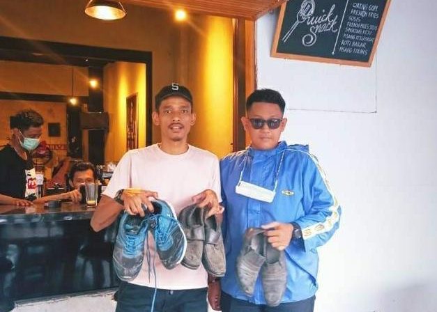 Founder Orangbike Messenger, Sandi Warasastra (kiri) saat menerima sumbangan sepatu. (@orangbikemessenger/Instagram)