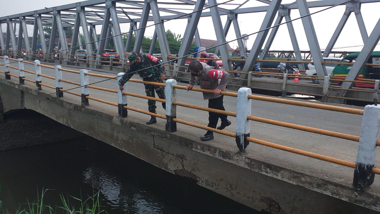 Petugas Polisi dan TNI sedang mengecek badan jembatan yang mengalami keretakan