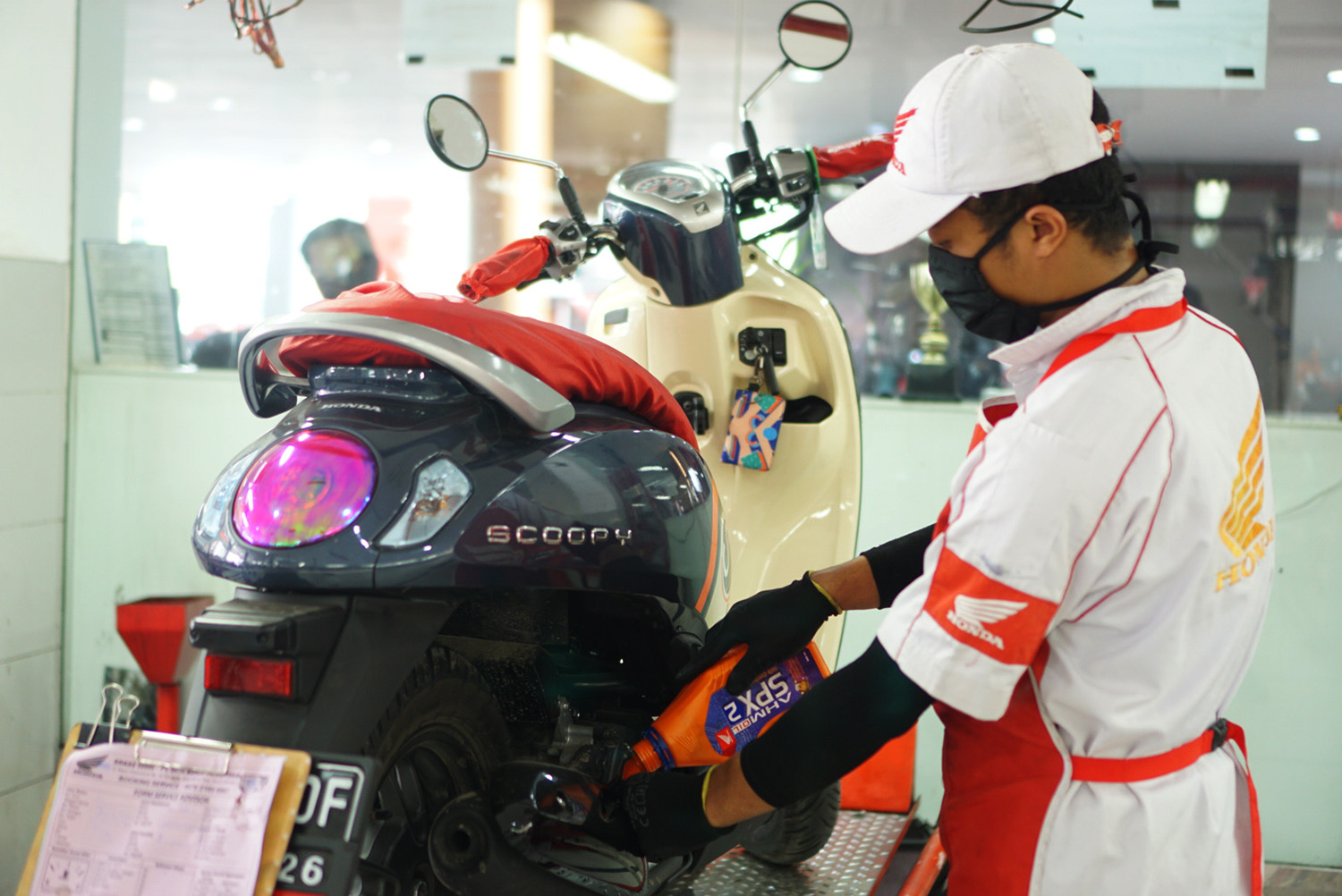 Perawatan motor Mekanik sepeda motor Honda mengganti oli mesin sepeda motor milik konsumen yang sedang servis di bengkel resmi Honda atau AHASS