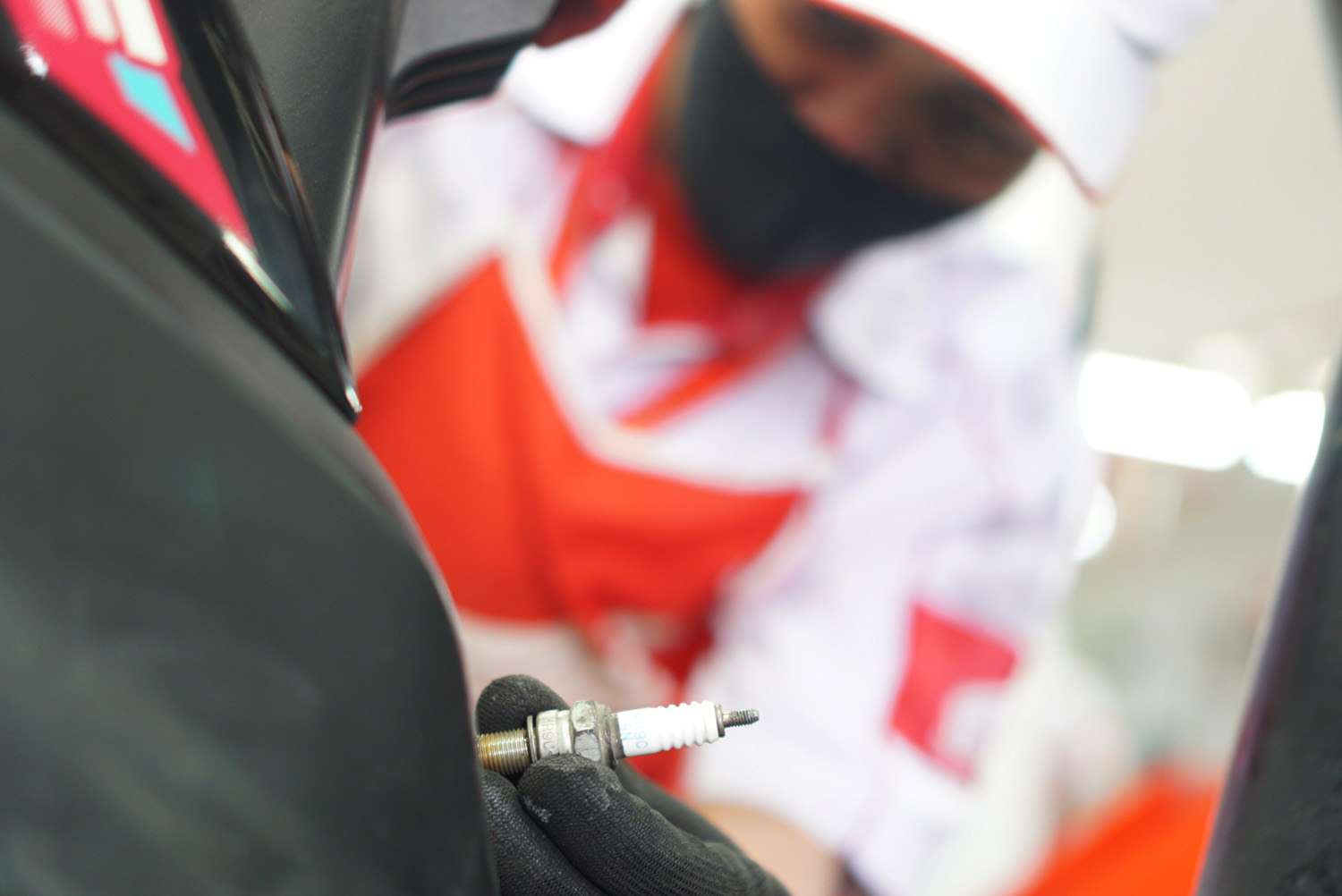 Perawatan motor Mekanik sepeda motor Honda mengganti busi sepeda motor milik konsumen yang sedang melakukan servis di bengkel resmi Honda atau AHASS