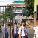 Seorang petugas mengecek suhu badan para siswa pada hari pertama pembelajaran tatap muka (PTM) terbatas di SMK Negeri 32 Jakarta, Tebet Dalam, Jakarta Selatan, Senin (30/8/2021). ANTARA/Sihol Hasugian