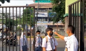 Seorang petugas mengecek suhu badan para siswa pada hari pertama pembelajaran tatap muka (PTM) terbatas di SMK Negeri 32 Jakarta, Tebet Dalam, Jakarta Selatan, Senin (30/8/2021). ANTARA/Sihol Hasugian