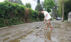 Seorang warga tengah membersihkan jalan dari kotoran sapi yang terbawa arus air hujan di Desa Kayu ambon lembang, beberapa waktu lalu. (Foto: Wisnu/ JabarEkspres)