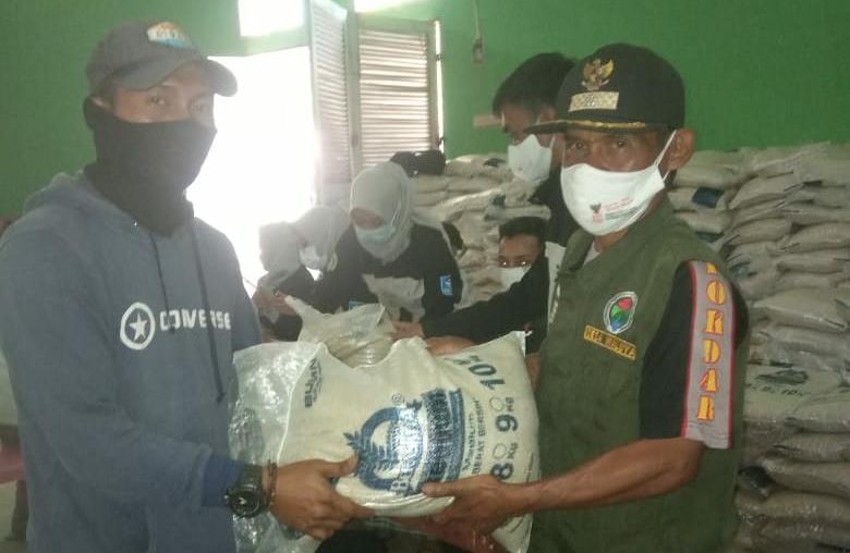 Kepala Desa Waluya, Aa Suryana (kanan) saat memberikan bantuan paket beras dari Kemensos kepada warga.