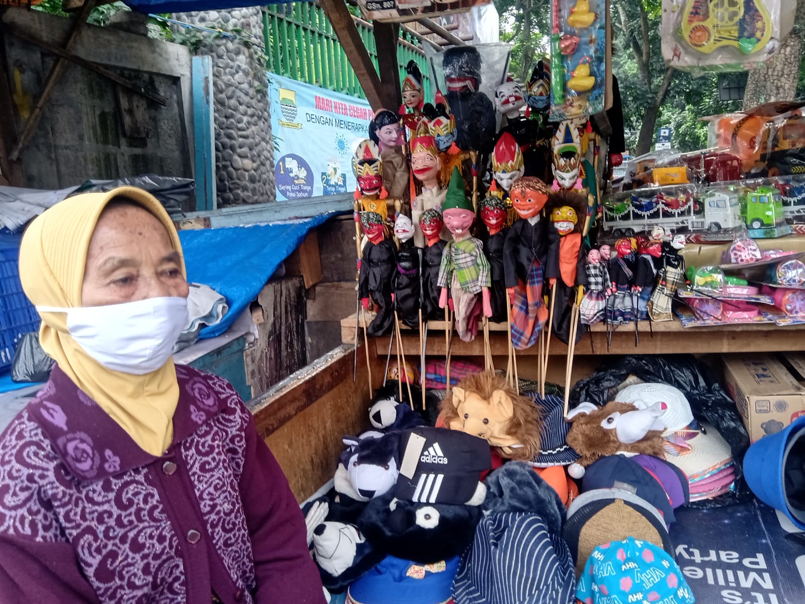 TERMENUNG - Enah menanti pengunjung yang biasanya datang untuk membeli dagangannya. Kini pendapatannya turun drastis, terdampak pandemi. Foto: Boy Darmawan, Jabar Ekspres