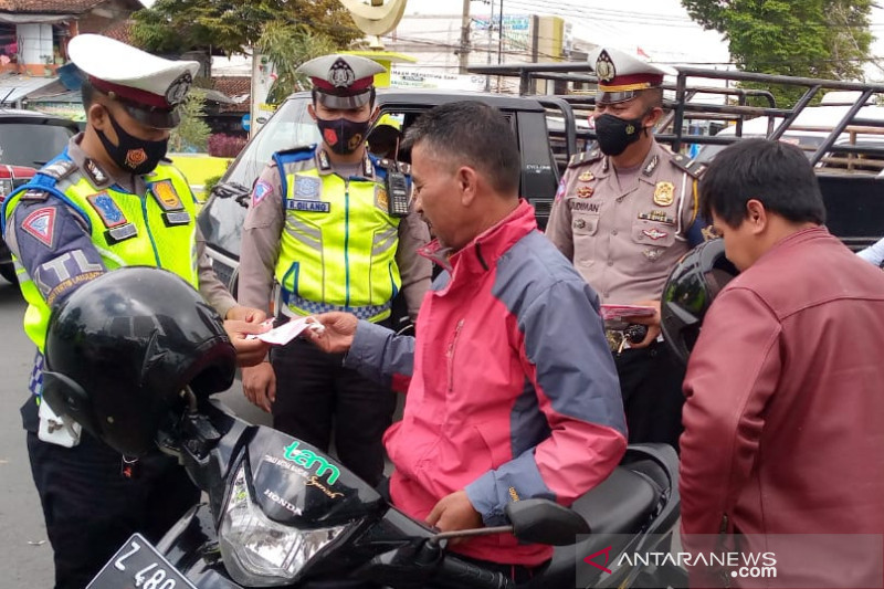 Sejumlah personel polisi membagikan masker kepada pengendara sepeda motor di Jalan Bunderan Suci, Kabupaten Garut, Jawa Barat, Senin (20/9/2021). (ANTARA/Feri Purnama)