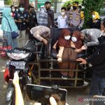 Polisi membantu putri kembar siam untuk menggunakan kursi roda dan sepeda motor yang sudah dimodifikasi di Karangpawitan, Kabupaten Garut, Jawa Barat, Jumat (3/9/2021). (ANTARA/Feri Purnama)