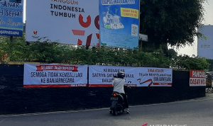 Seorang warga memotret spanduk yang terpasang di sekitar Alun-Alun Banjarnegara, Sabtu (4/9/2021), salah satunya bertuliskan ucapan terima kasih kepada KPK. (ANTARA/Sumarwoto)