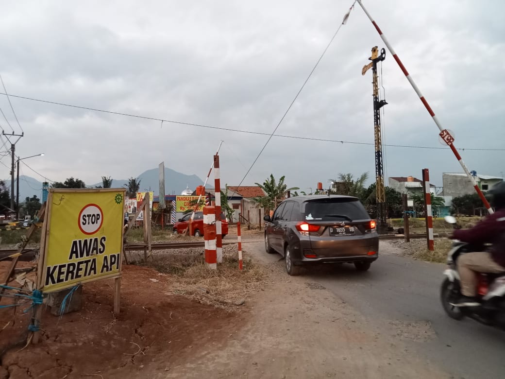 Kendaraan melintas di jalur rel Kereta Api Cimekar tanpa palang pintu otomatis.