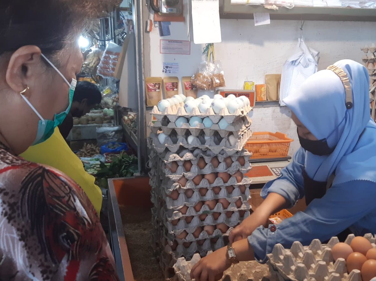 BERJUALAN: Pedagang telur tengah melayani pembeli.