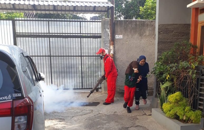 Petugas kesehatan melakukan fogging di lingkungan rumah warga.