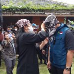 Abah Ande menyematkan ikat kepala kepada Kadis DPMD Jabar H Dicky Saromi pada acara vaksinasi massal di Kampung Adat Ciptarasa Kabupaten Sukabumi.