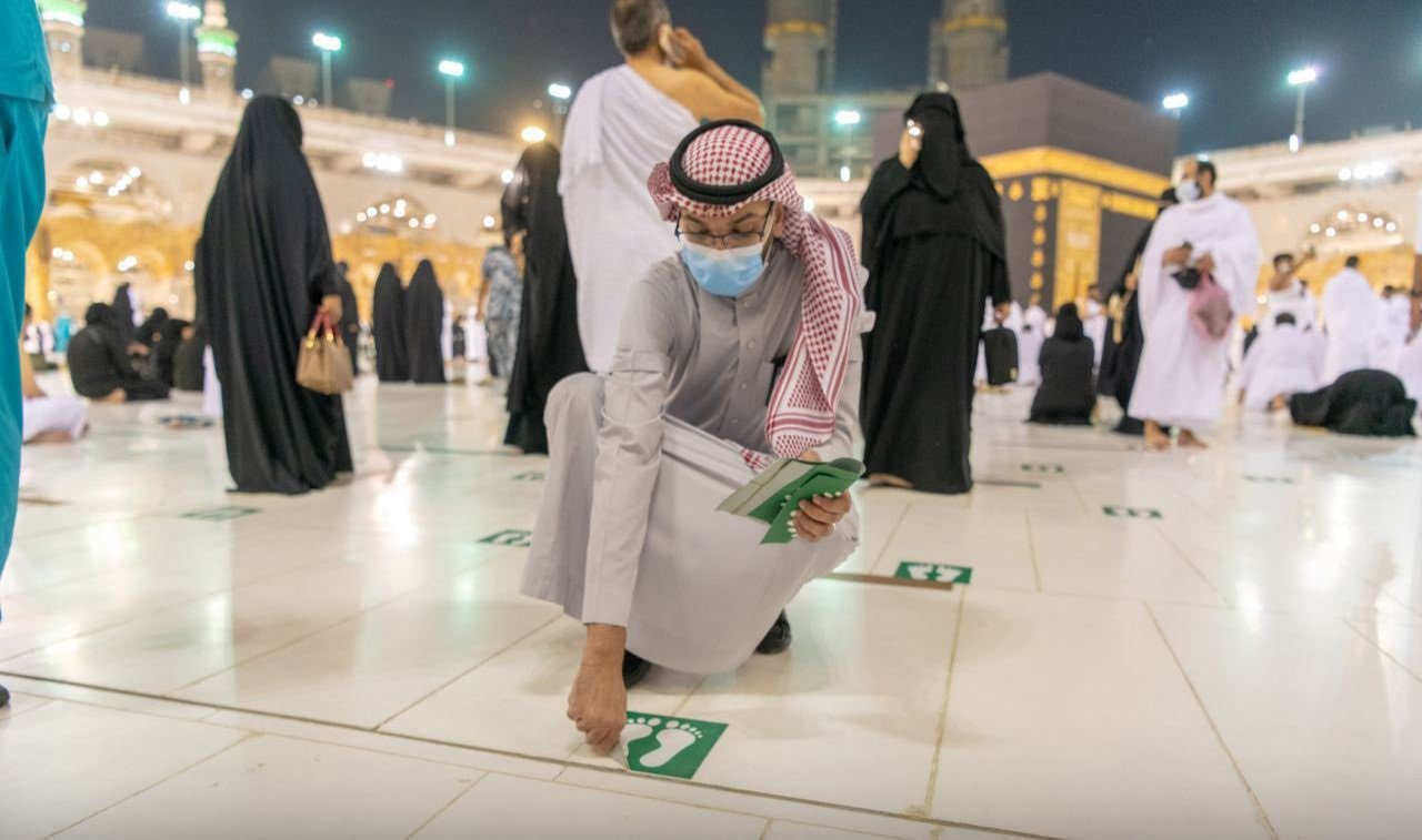 Petugas di Masjidil Haram Makkah membuka tanda stiker jaga jarak bagi para jamaah