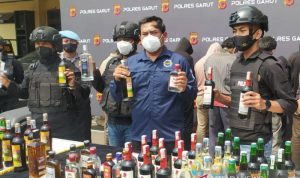 Polisi menunjukkan barang bukti minuman keras dan penjual hasil operasi pemberantasan minuman keras di Kabupaten Garut, Jawa Barat, Selasa (12/10/2021). (ANTARA/Feri Purnama)