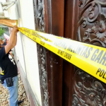 Anggota Tim Puma Polresta Mataram memasang garis polisi di rumah SO alias Titi yang ditempati tersangka judi togel, Selasa lalu (19/10). (Harli/Lombok Post)