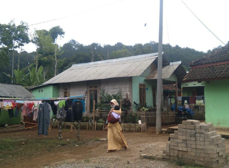 Salah seorang warga Kampung Cigumentong saat berjalan melewati tiang listrik baru. (Yanuar Baswata/Jabar Ekspres)