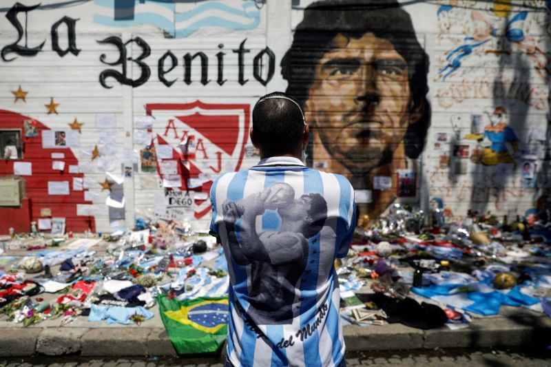Seorang pria memandangi gambar legenda sepak bola Diego Armando Maradona sambil berduka atas kematiannya di depan stadion yang mengambil namanya di Buenos Aires, Argentina, Jumat (27/11/2020). ANTARA FOTO/REUTERS/Ricardo Moraes/HP/djo (REUTERS/RICARDO MORAES)