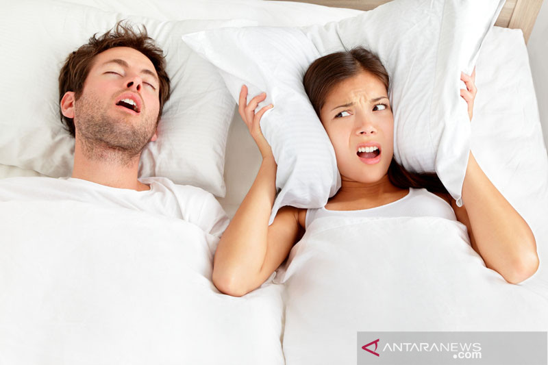 Ilustrasi - Pria mendengkur. Pasangan di tempat tidur, pria mendengkur dan wanita tidak bisa tidur, menutupi telinga dengan bantal untuk suara dengkuran. ANTARA/Shutterstock/pri.