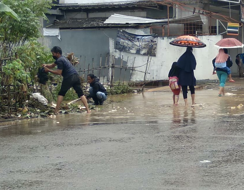 Warga Desa Cikuya, Kecamatan Cicalengka, Kabupaten Bandung (ujung kiri) saat membersihkan sumbatan saluran air karena sampah. (Jabar Ekspres)