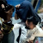 Dosen Unsri pelaku pelecehan seksual kepada mahasiswi saat digiring keluar dari ruang penyidikan di Markas Polda Sumatera Selatan pada Senin (6/12/2021). (ANTARA/M Riezko Bima Elko P/21)