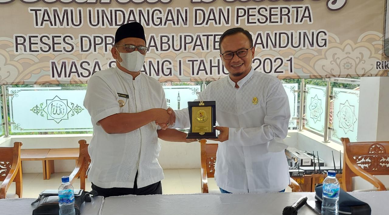 Anggota Komisi A DPRD Kabupaten Bandung Fraksi Golkar, Riki Ganesa memberikan plakat kepada Kepala Desa Cinunuk Karena telah mensukseskan Vaksin Covid-19. (Yully S Yulianty/Jabar Ekspres)
