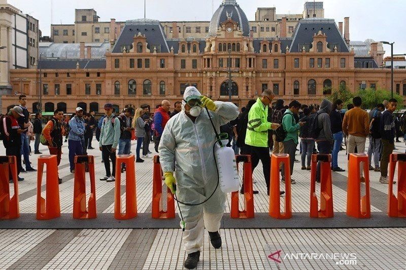 Petugas menyemprotkan desinfektan di pintu masuk stasiun kereta bawah tanah di Buenos Aires, Argentina, 2020. Argentina diterpa gelombang baru Covid-19. (ANTARA/Reuters)