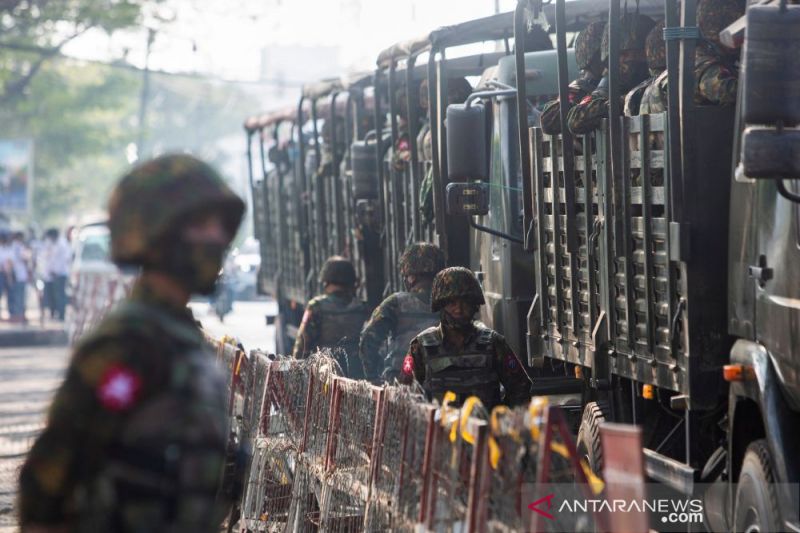 Ilustrasi: Tentara berdiri di samping kendaraan militer ketika orang-orang berkumpul untuk memprotes kudeta militer di Yangon, Myanmar, 15 Februari 2021. (REUTERS/Stringer)