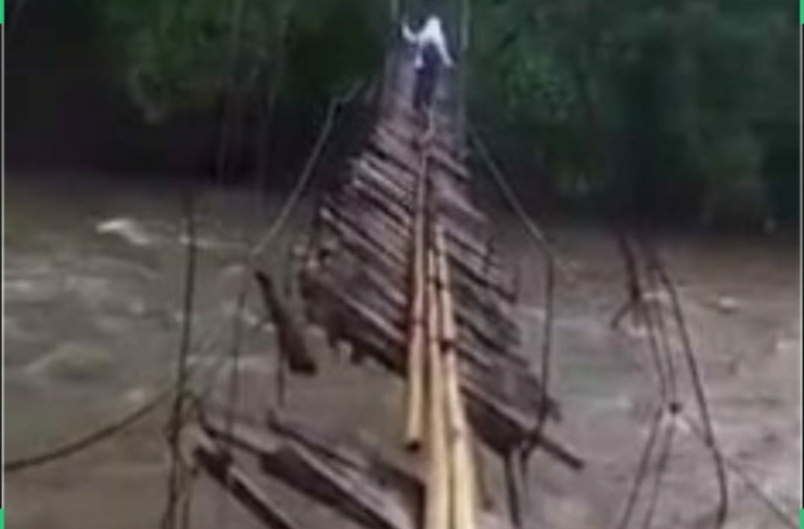 Tangkapan layar video yang memperlihatkan kondisi jembatan yang nyaris putus sangat membahayakan seorang pelajar yang berusaha melintasinya.