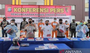 Dirjen Pas Kemenkumham Reynhard (kiri) bersama Kepolisian Polda Riau memegang barang bukti pembakaran mobil dinas Lapas Pekanbaru. (Antara)