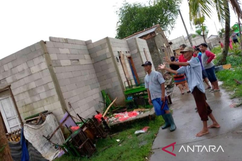Tetangga Masuti bergotong royong membersihkan puing-puing atap rumahnya yang hancur tersapu angin puting beliung, Selasa (15/2/2022) sore. (FOTO ANTARA/Pradita Kurniawan Syah).