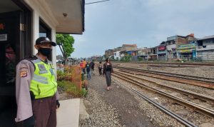 Seorang petugas keamanan sedang mengawasi rel kereta api di Pasar Ciroyom, Rabu (16/02/2022)./ Arvi Resvanty