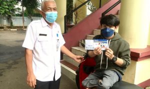 Sekcam Cimanggis, Bambang Eko Sukmono (kiri) menyerahkan kartu KDS sebagai bantuan sosial pada penerimanya, istimewa.