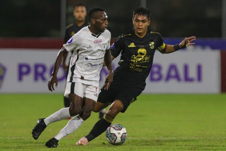 Kapten Persebaya Rachmat Irianto (kanan) mengawal pemain Persipura Elisa Basna dalam lanjutan Liga 1 2021-2022. (Riana Setiawan/Jawa Pos)
