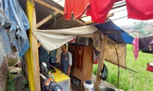BERHARAP BANTUAN: Dedi Hermawan, 35, tampak sedang bersih bersih rumahnya yang semalaman kebocoran akibat hujan. Dia sudah enam tahun tinggal di rumah yang tidak layak huni tersebut.