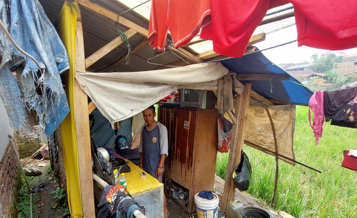 BERHARAP BANTUAN: Dedi Hermawan, 35, tampak sedang bersih bersih rumahnya yang semalaman kebocoran akibat hujan. Dia sudah enam tahun tinggal di rumah yang tidak layak huni tersebut.