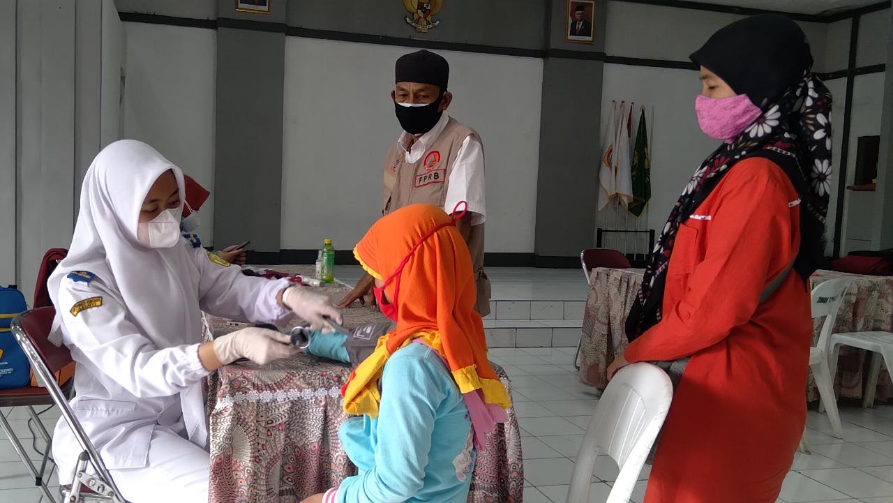 Seorang tenaga kesehatan tengah memeriksa kondisi anak peserta vaksin di Balai Desa Sindangpakuon, Kecamatan Cimanggung, Kabupaten Sumedang. (Jabar Ekspres)