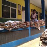 Kepala Sekolah SDN 07 Rancaekek, Suparyana tengah memilah dan menjemur buku yang rusak serta basah akibat banjir bandang. (Jabar Ekspres)