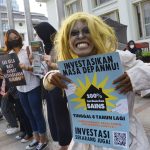 Foto: Seorang pengunjuk rasa membentangkan poster di sekitar Gedung Merdeka, Jalan Asia Afrika, Bandung, Jumat (25/3). (Foto: Dimas Rachmatsyah)