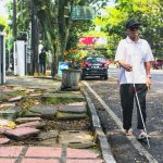 TUNANETRA: Seorang penyandang disabilitas tunanetra saat menggunakan bahu jalan, lantaran trotoar rusak dan membahayakan. (Deni/Jabar Ekspres)