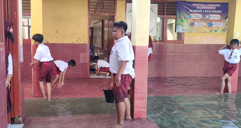 Kondisi sekolah yang terendam banjir, siswa terpaksa membantu menguras air agar bisa melaksanakan ujian. ( FOTO MELIDA ROHLITA/RADARLAMPUNG.CO.ID)