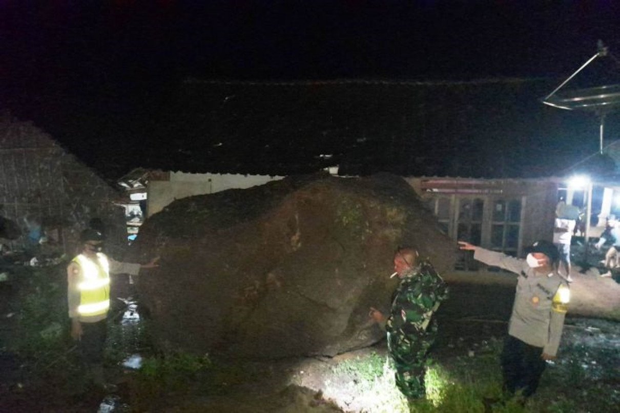 Petugas menunjukkan Bongkahan batu sebesar mobil yang menimpa rumah warga, saat akan di evakuasi. (ANTARA/HO-istimewa)
