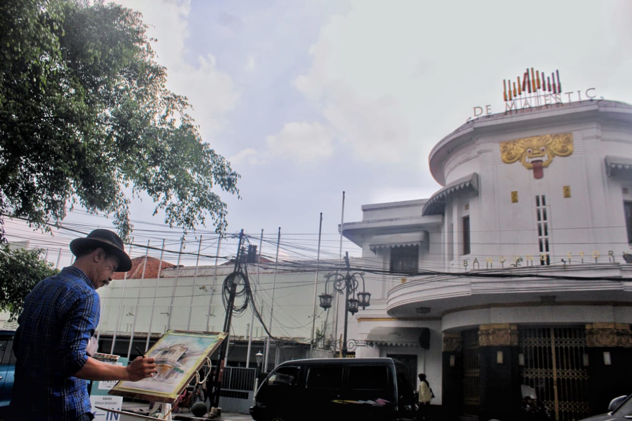 MEIGAMBAR: Pelukis, Yus Arwidanata tengah melukis kondisi di sepanjang Jalan Asia-Afrika dan Merdeka, Kota Bandung. (Deni/Jabar Ekspres)
