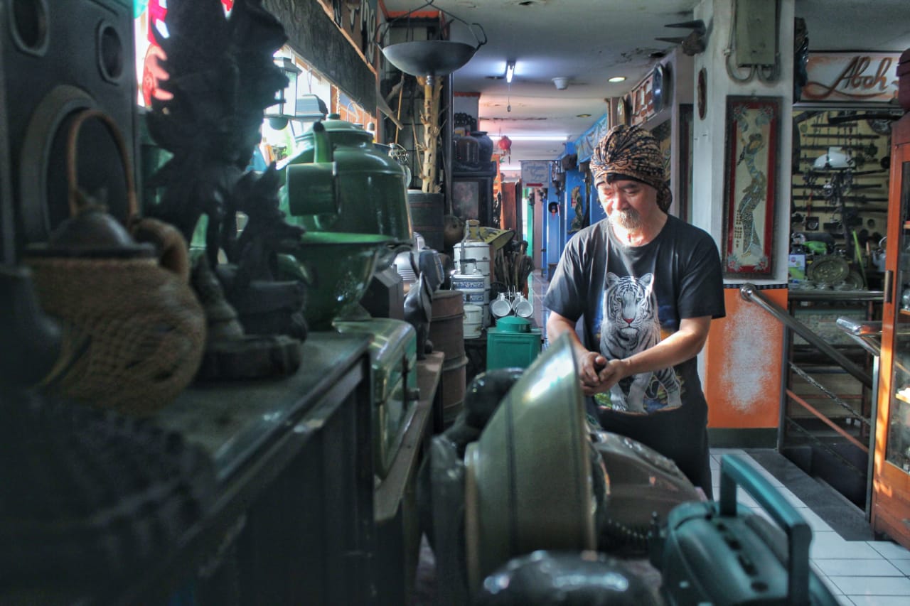 MENATA: Pedagang benda antik, Abah Kepret, (70), tengah sibuk menata barang-barang jualannya di Pasar Antik Cikapundung, Kota Bandung. (Deni/Jabar Ekspres)