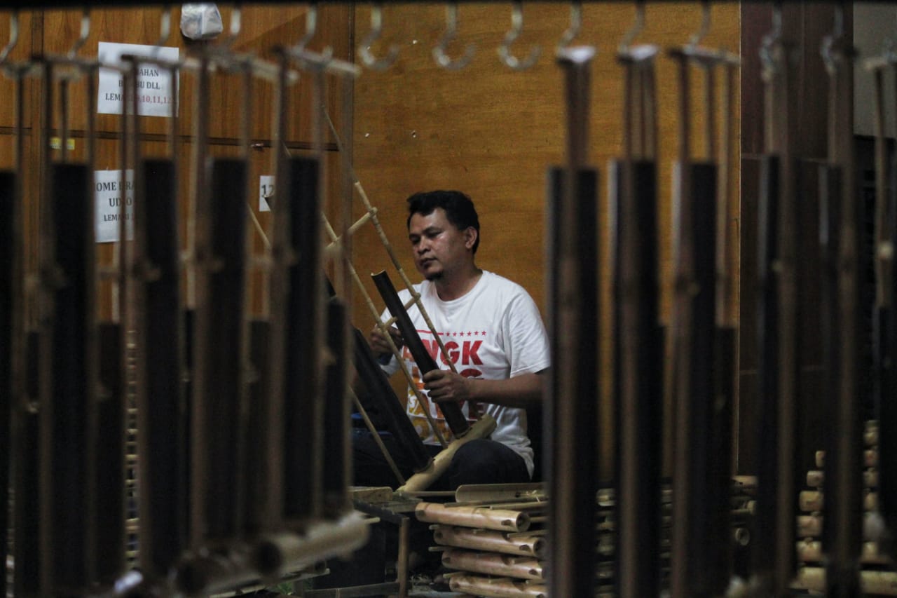 MEMOLES: Perajin angklung, Adang (37) melakukan proses tahap akhir pengecekan nada di ruang perajin Saung Angklung Udjo, Kota Bandung. (Deni/Jabar Ekspres)