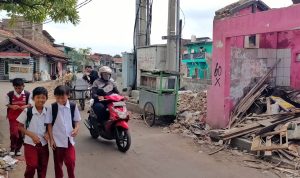 Beberapa anak-anak pulang sekolah dengan melewati jalan yang ada didekat bantaran sungai dan puing-puing rumah yang dibongkar oleh Satgas Citarum Harum