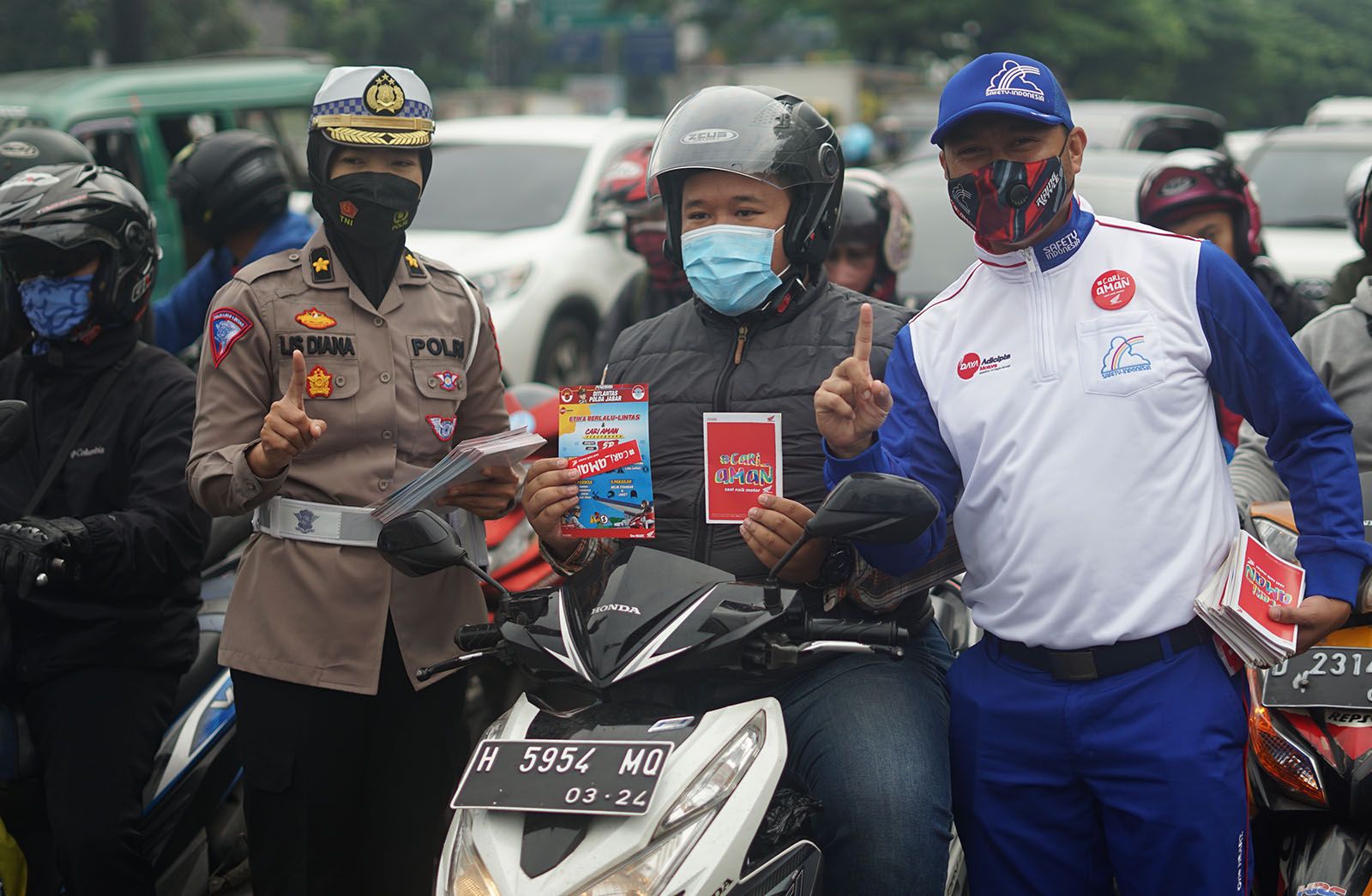 Pemberian buku pedoman keselamatan berlalu lintas oleh Safety Riding Development Section Head PT Daya Adicipta Motora, Ludhy Kusuma dan Kompol Iis Diana.